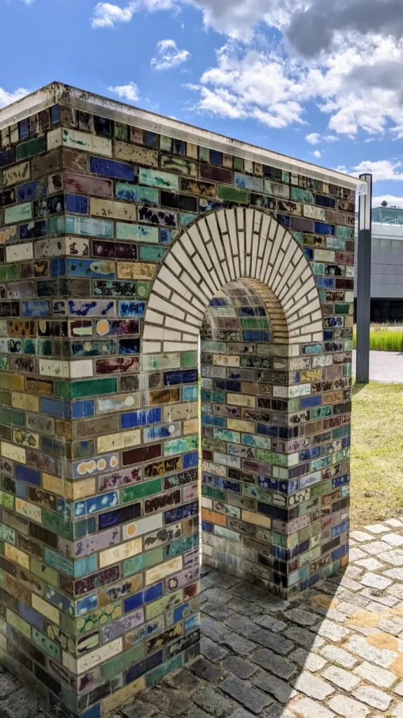 Bogen aus bunt glasierten Ziegeln zwischen Bäumen auf dem Wissenschaftscampus in Berlin-Adlershof