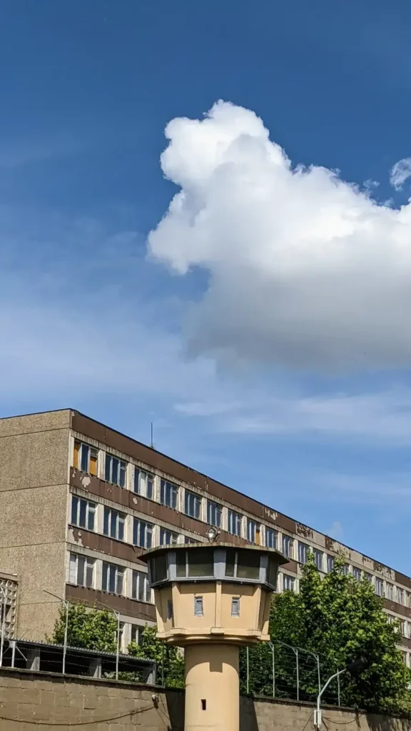 Wachturm am Gelände der Gedenkstätte an der Genslerstraße, dahinter ein Plattenbau