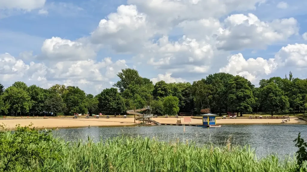 Sandstrand des Strandbads am Orankesee in Alt-Hohenschönhausen mit Wasser und Bäumen am Ufer