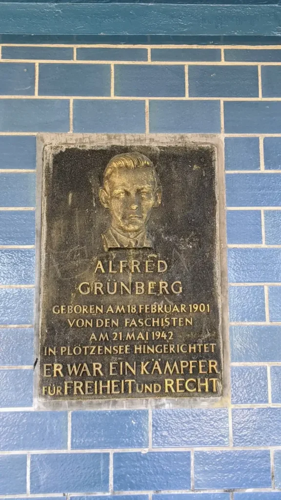Gedenktafel für den Widerstandskämpfer Alfred Grünberg an einer blau gefliesten Wand am S-Bahnhof Grünbergallee