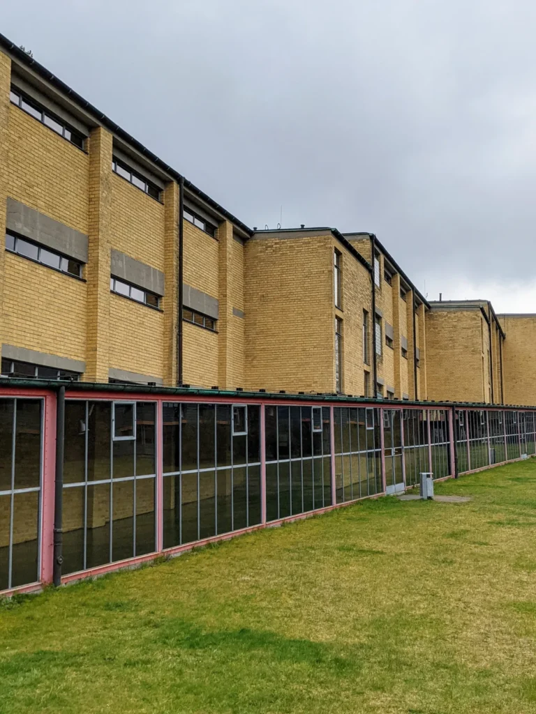 Gelbe Klinkerfassade der früheren ADGB-Bundesschule in Bernau mit langem verglastem Gang und rosa Rahmen