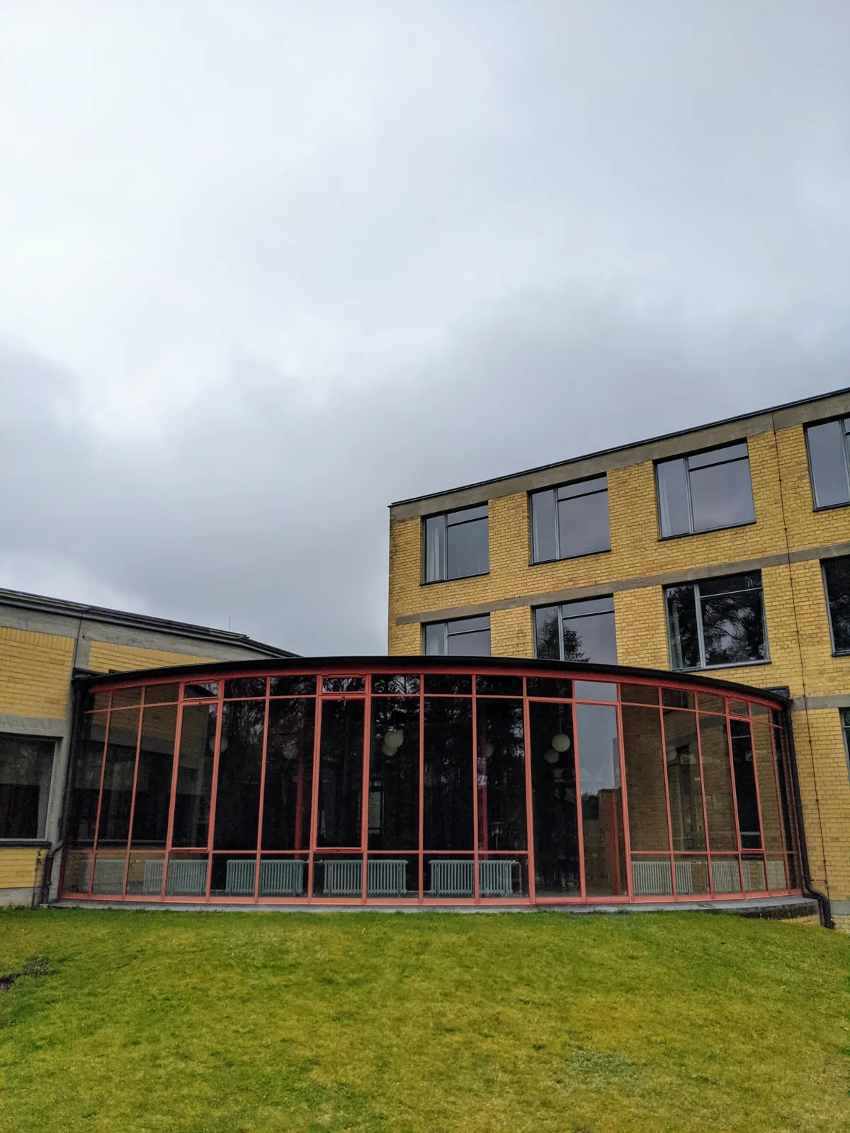 Gebogene Glasfront mit rot gestrichenen Rahmen an der früheren ADGB-Bundesschule in Bernau, dahinter gelbe Klinkerfassade