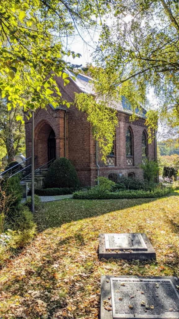 Backsteinkirche der Anstalt Wuhlgarten in Biesdorf mit zwei Gedenkplatten im Rasen davor