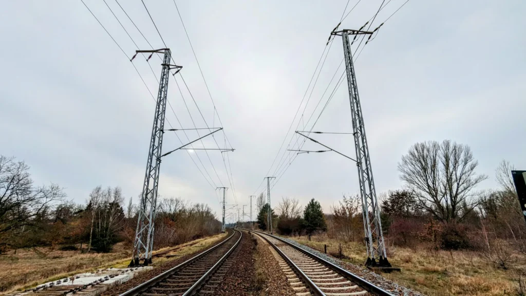 Gleise mit Oberleitung neben dem Weg