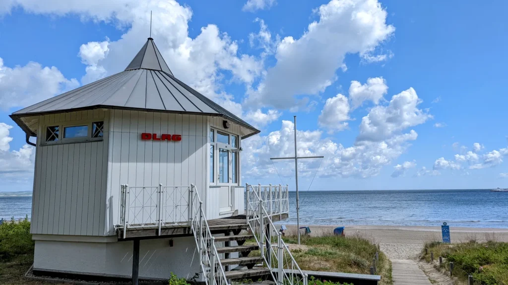 Weißes Holzhaus der DLRG-Station mit Treppe am Strand von Binz, dahinter die Ostsee