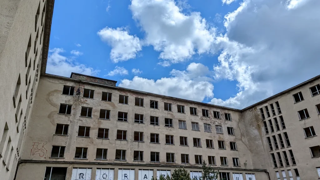 Unsanierter Block in Prora mit verwitterter Fassade und Buchstaben in den Fenstern