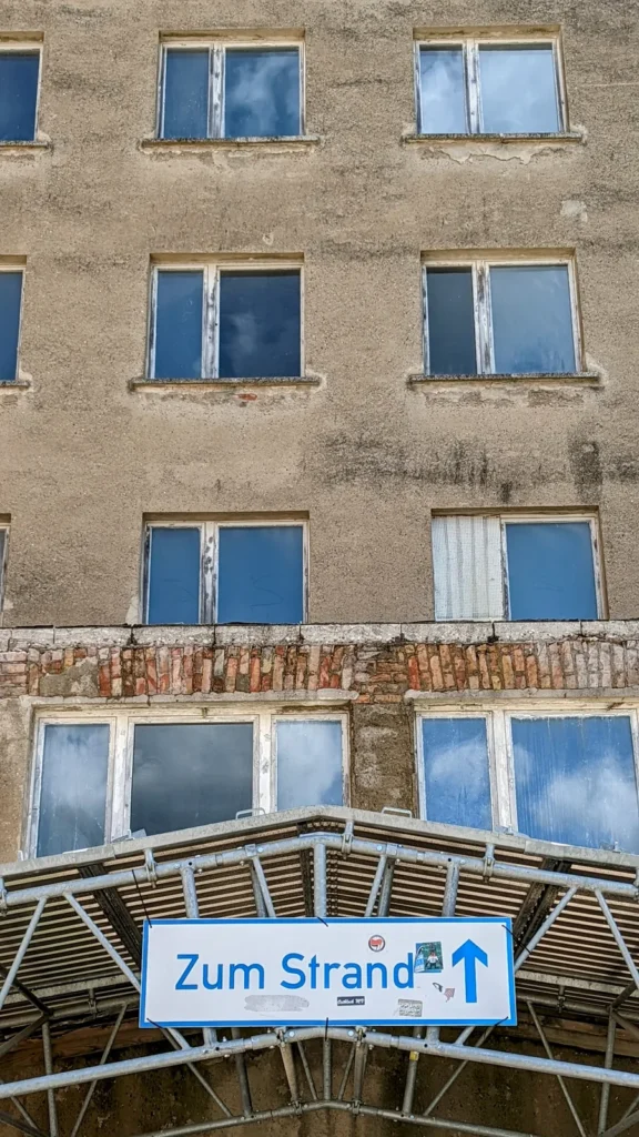 Unsanierte Fassade in Prora mit Schild Zum Strand über einem Durchgang
