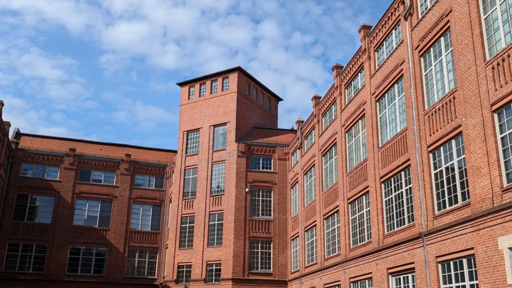 Mehrgeschossige Fabrikbauten aus rotem Backstein mit großen Sprossenfenstern an der Geschwister-Scholl-Straße