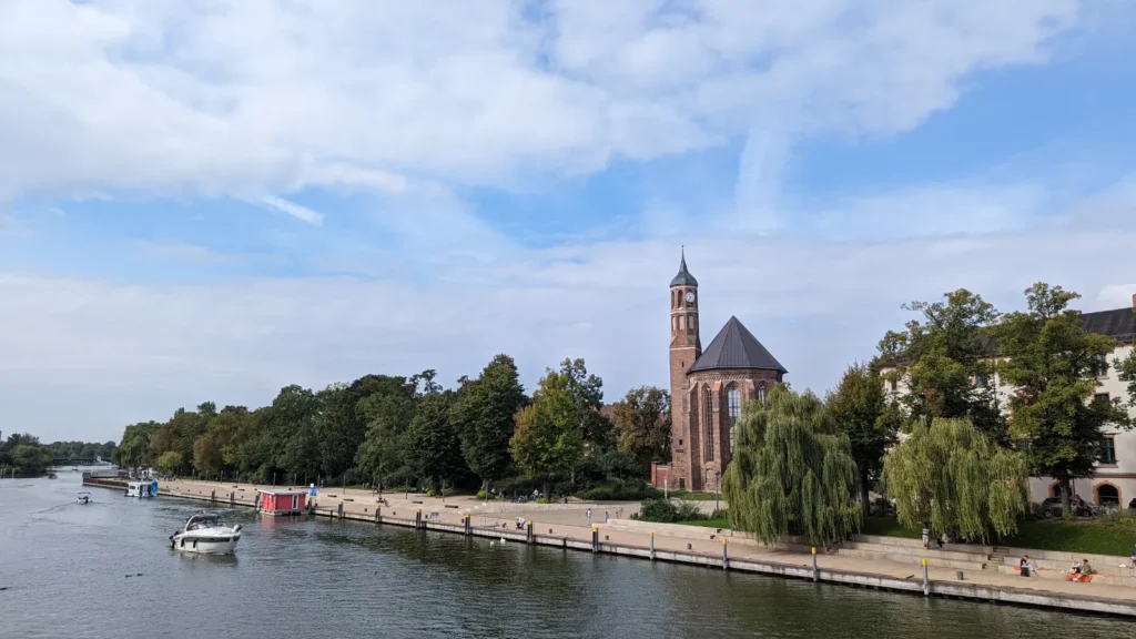 Havel mit Booten und Uferpromenade, am anderen Ufer die Kirche St. Johannis mit ihrem schlanken Turm