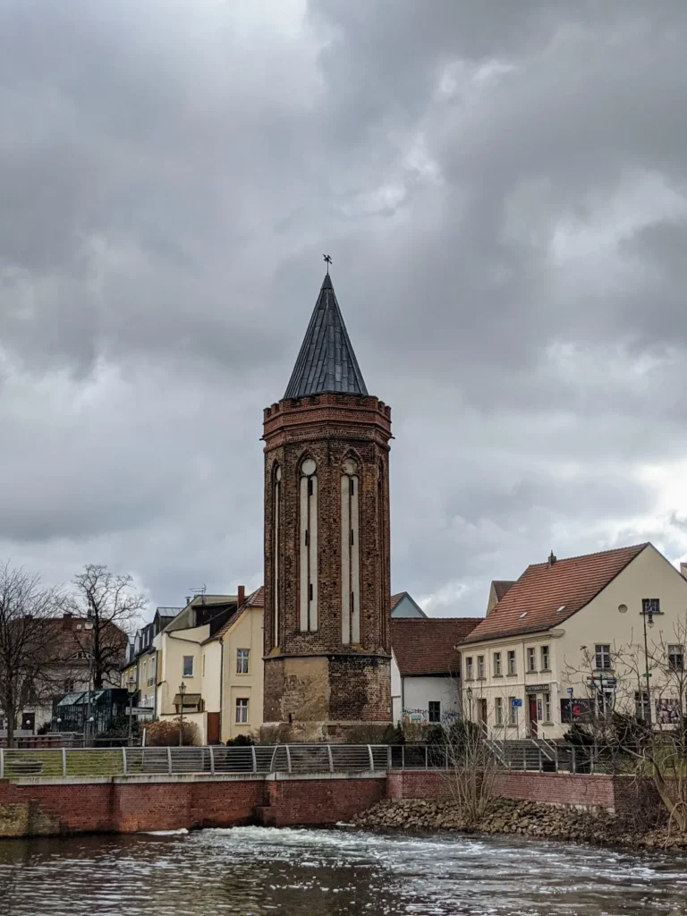 Achteckiger Neustädtischer Mühlentorturm aus Backstein mit spitzem Helm, davor ein Wehr an der Havel