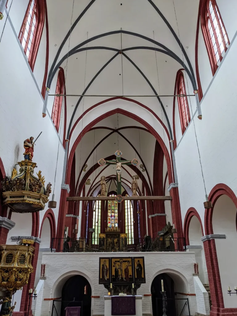 Blick durch das Mittelschiff des Brandenburger Doms auf den erhöhten Chor, weiße Wände mit roten Gewölberippen