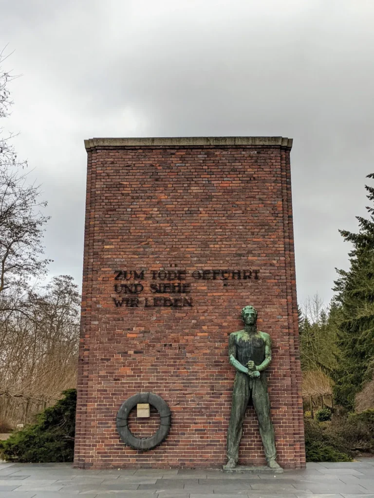 Mahnmal am Marienberg: Bronzefigur eines Mannes mit gefesselten Händen vor einer Ziegelwand mit der Inschrift Zum Tode geführt und siehe wir leben