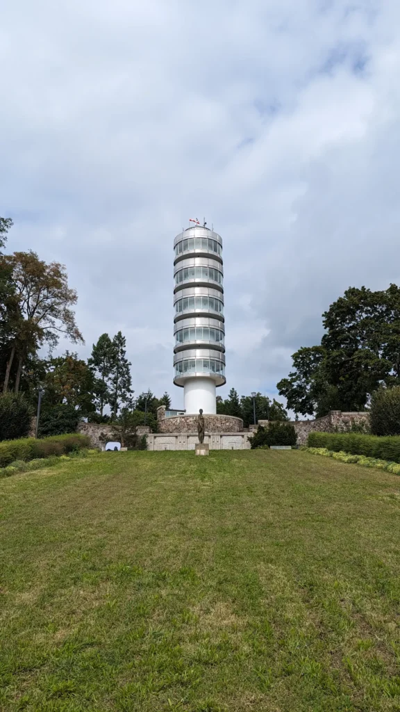 Friedenswarte auf dem Marienberg, ein schlanker Aussichtsturm aus Edelstahl und Glas über einer Wiese