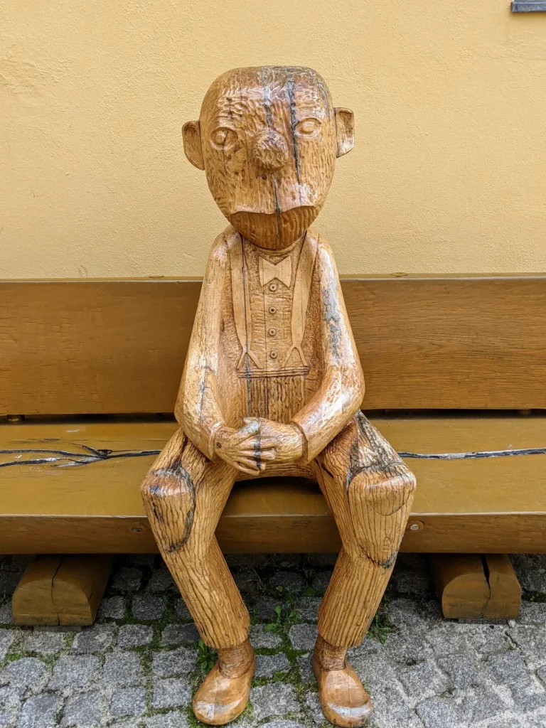 Holzfigur eines Knollennasenmännchens nach Loriot, das auf einer Bank am Altstädtischen Markt sitzt