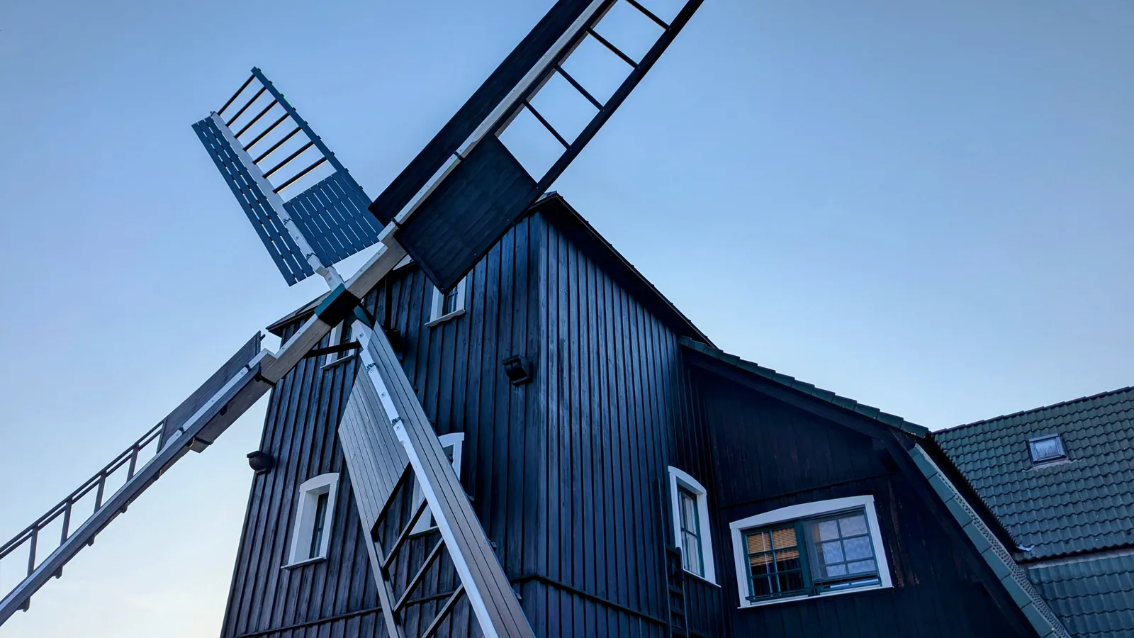 Dunkle Holzwindmühle mit Flügeln auf dem Kräutermühlenhof in Burg