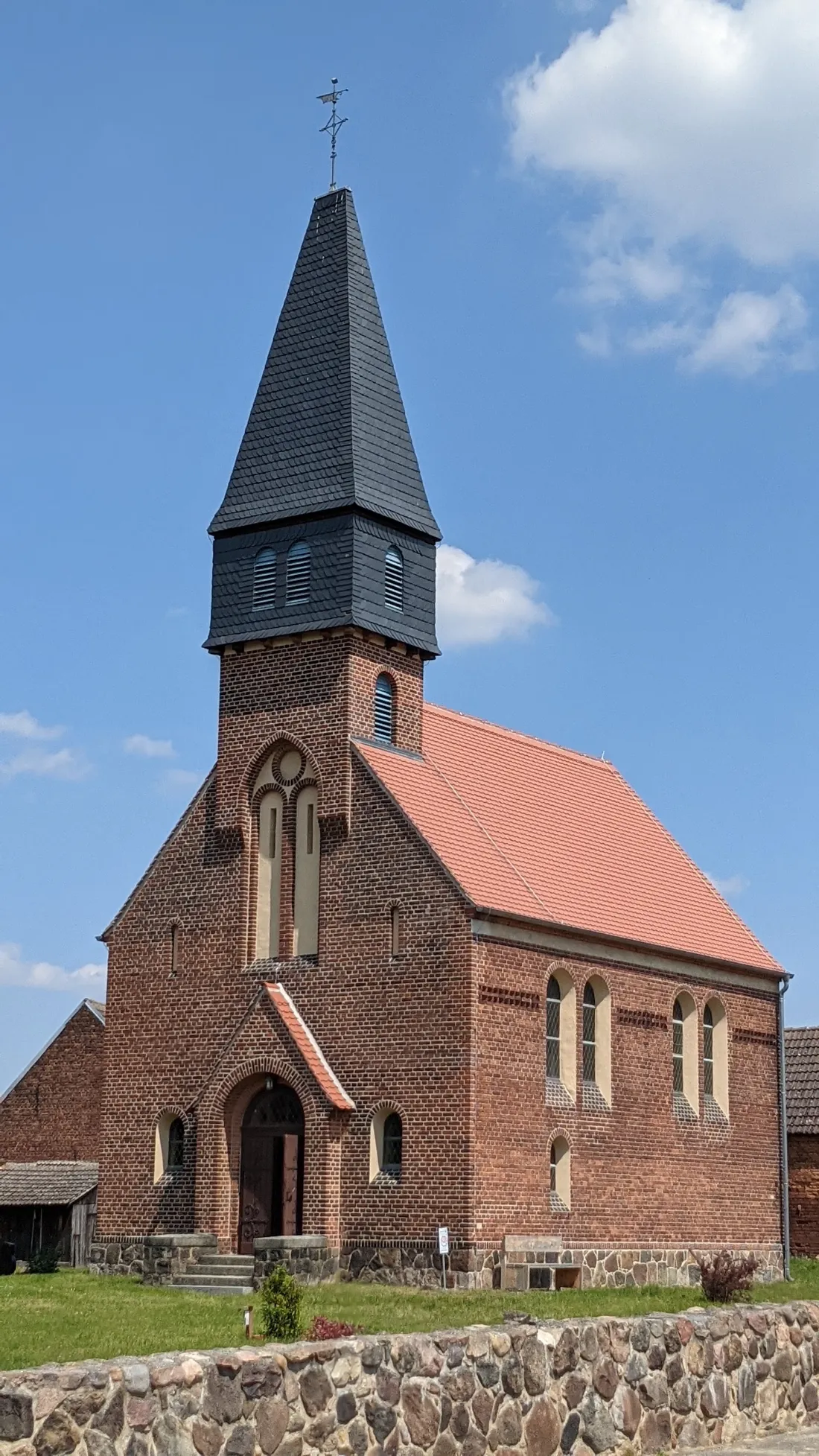 Backsteinkirche mit spitzem Turm in Lühnsdorf