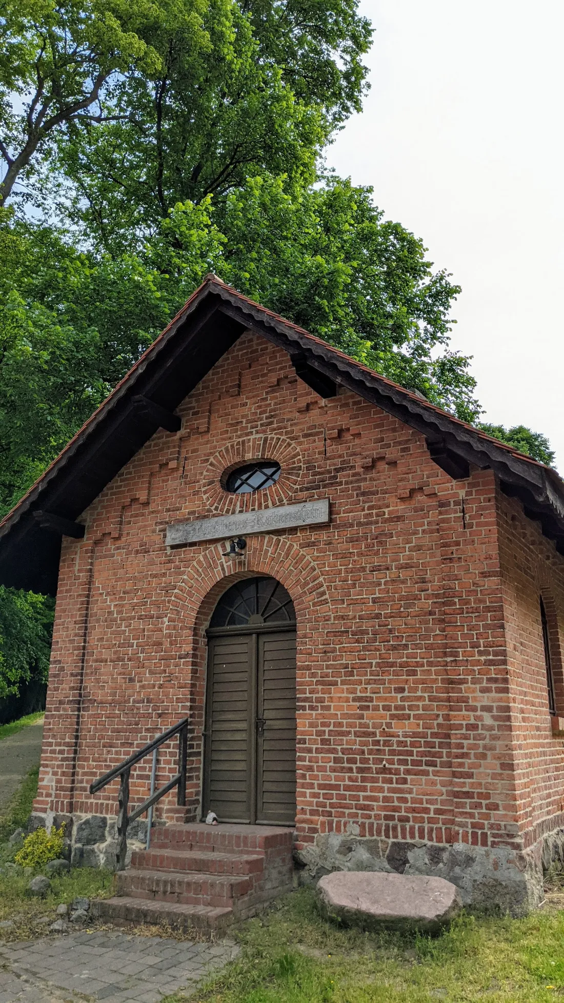 Kleines Backsteinhaus mit Rundbogentür am Weg