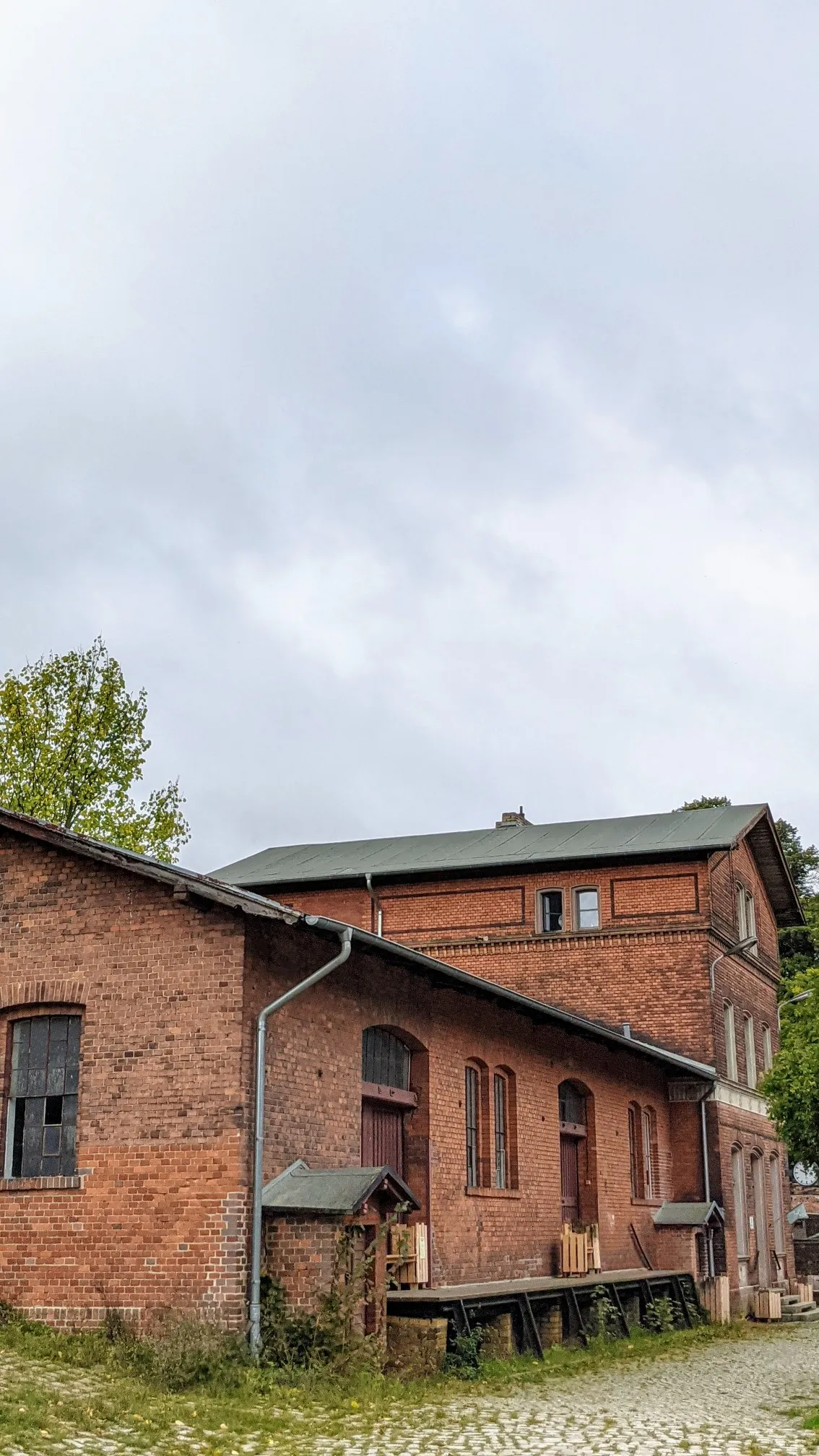 Rotes Backsteingebäude am Bahnhof Wiesenburg mit Kopfsteinpflaster davor