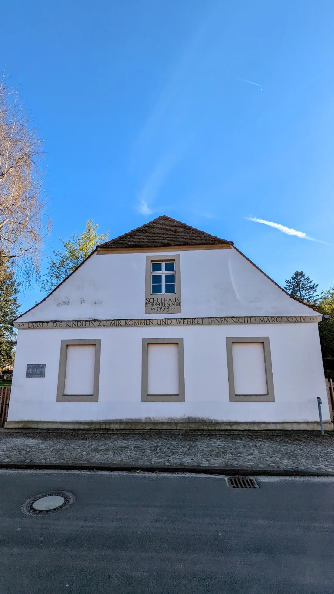 Weißes Schulhaus in Reckahn mit Inschrift und Putzfeldern