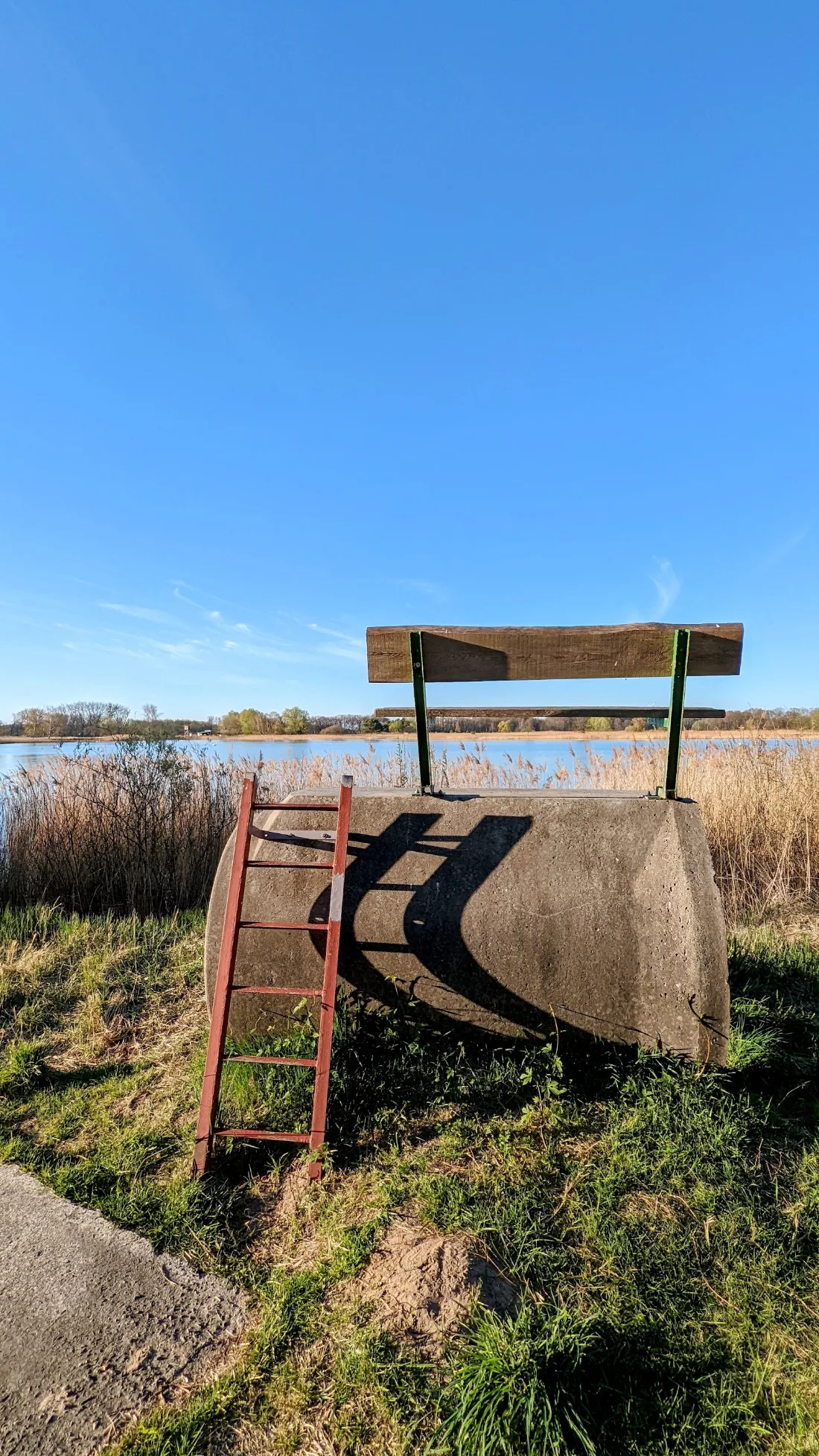 Holzbank auf einem Betonrohr am Teich