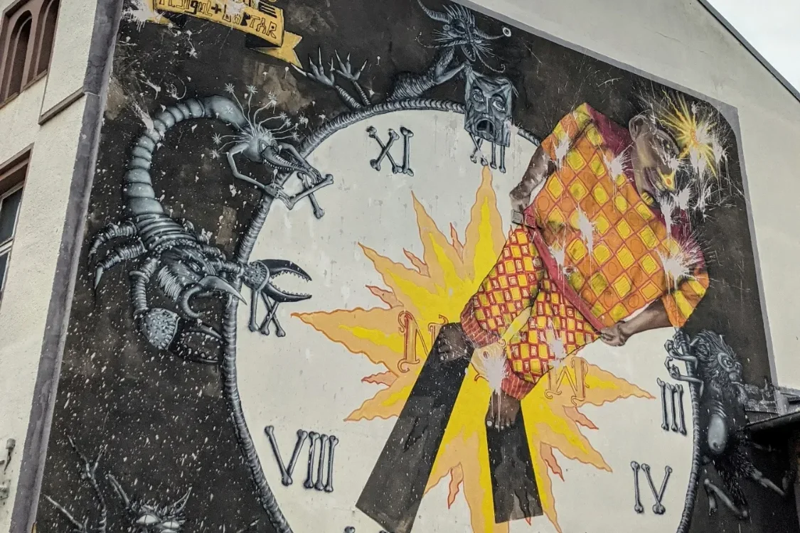 Wandbild „NOW“ von Captain Borderline an der Bachstraße in Lutherstadt Wittenberg: große Uhr mit römischen Ziffern auf schwarzem Grund