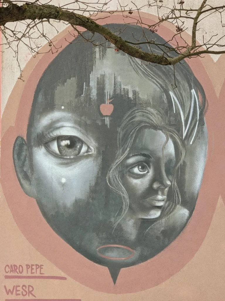 Wandbild von Caro Pepe und WESR an der Fanny-Zobel-Straße in Berlin-Treptow: graues, ovales Gesicht mit Kinderauge und Frauenprofil auf rosa Grund