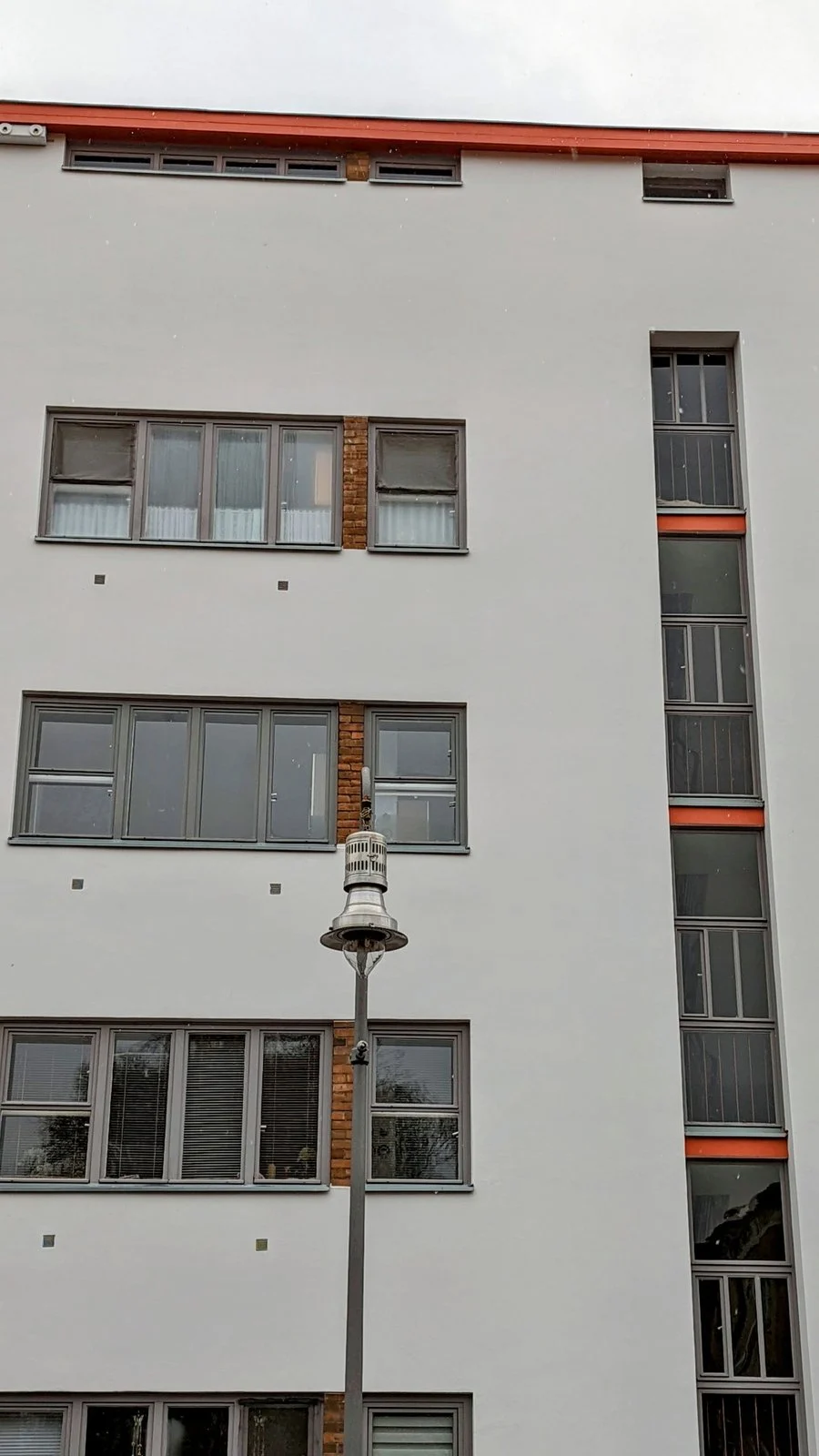 Weiß verputzter Wohnbau mit orangefarbenen Streifen im Bereich der Ringsiedlung Siemensstadt