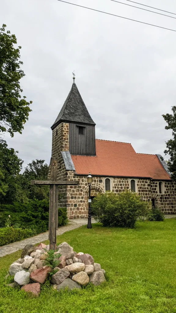 Dorfkirche Apollensdorf aus Feldstein mit Turm, davor eine Wiese