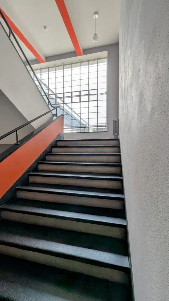 Treppe mit roter Untersicht und großem Fenster im Bauhausgebäude in Dessau
