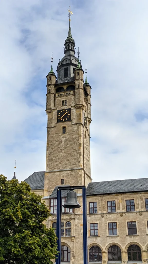 Rathausturm in Dessau mit Uhr, davor die Friedens- und Freiheitsglocke in einem blauen Gerüst