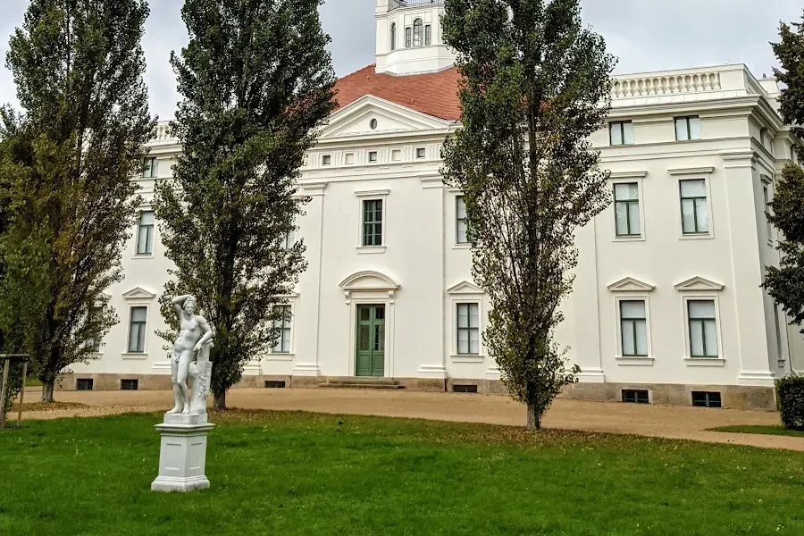 Schloss Georgium in Dessau hinter Pyramidenpappeln, davor eine Statue