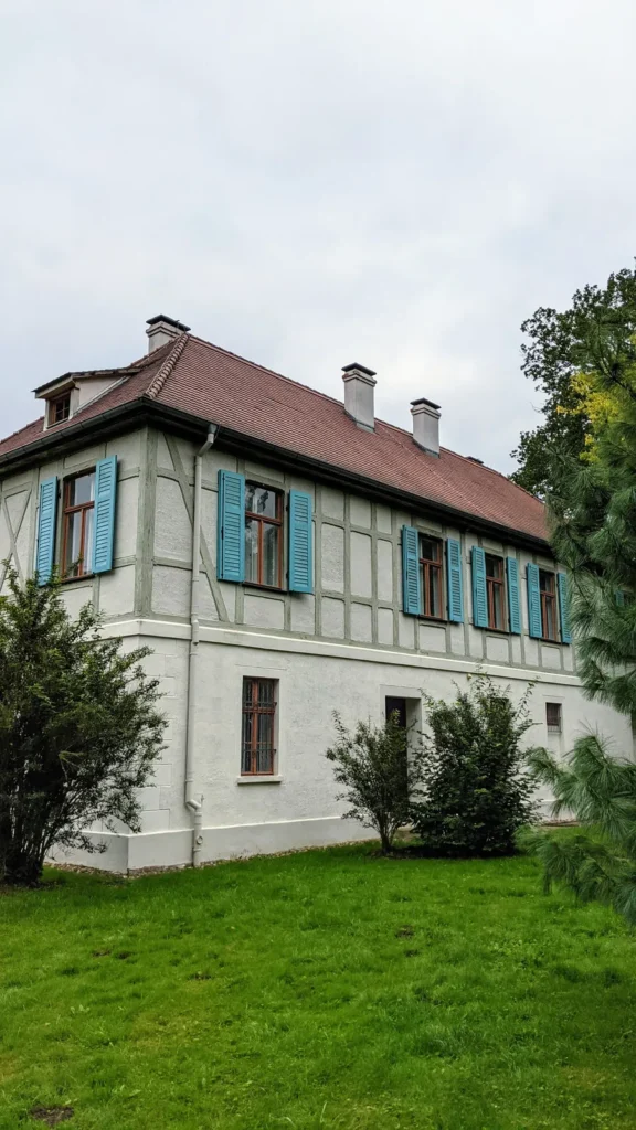 Haus mit Fachwerk im Obergeschoss und türkisen Fensterläden im Park Luisium