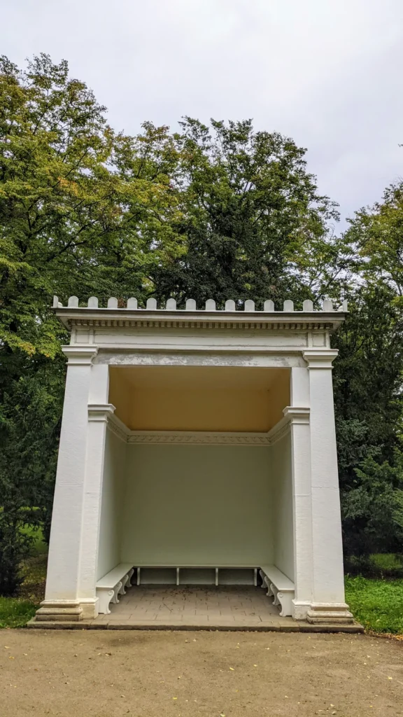Weiße offene Sitznische mit Bänken im Park Luisium