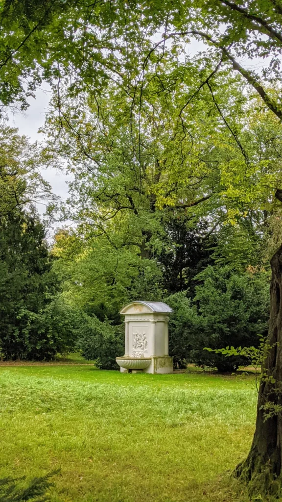 Weißer Wandbrunnen auf einer Wiese im Park Luisium