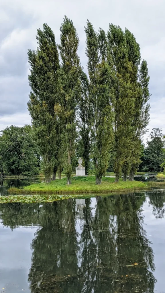 Rousseauinsel im Wörlitzer Park mit hohen Pappeln und einer hellen Urne, die sich im Wasser spiegeln