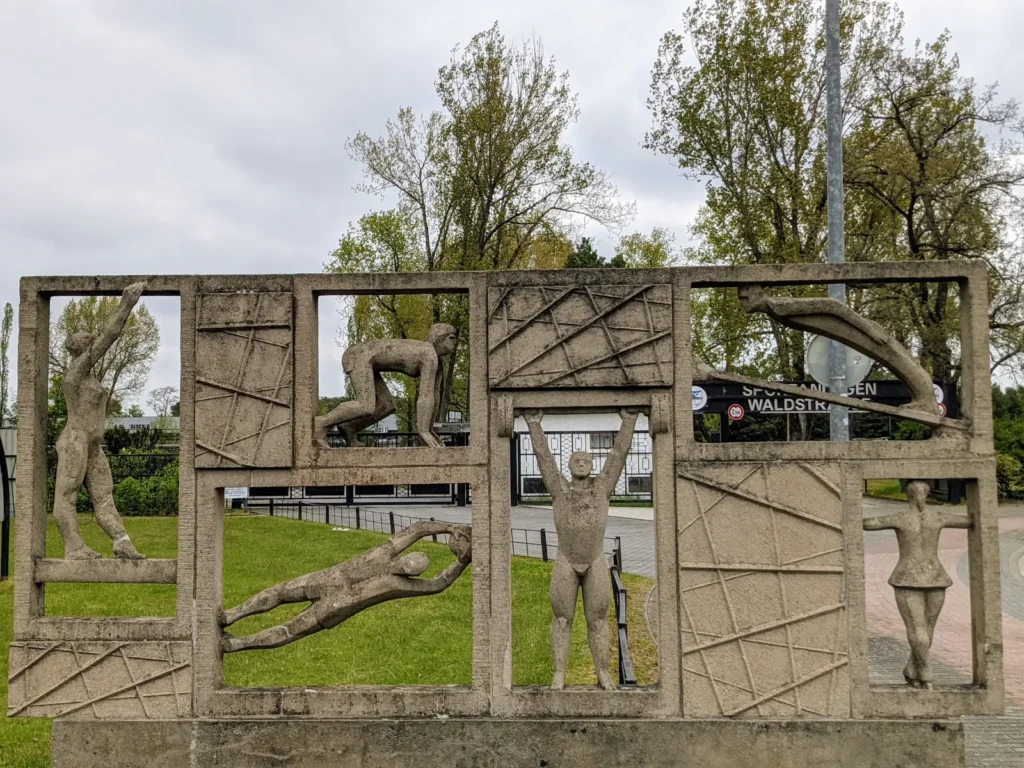 Durchbrochene Betonwand mit Sportlerfiguren am Eingang der Sportanlagen Waldstraße in Eisenhüttenstadt