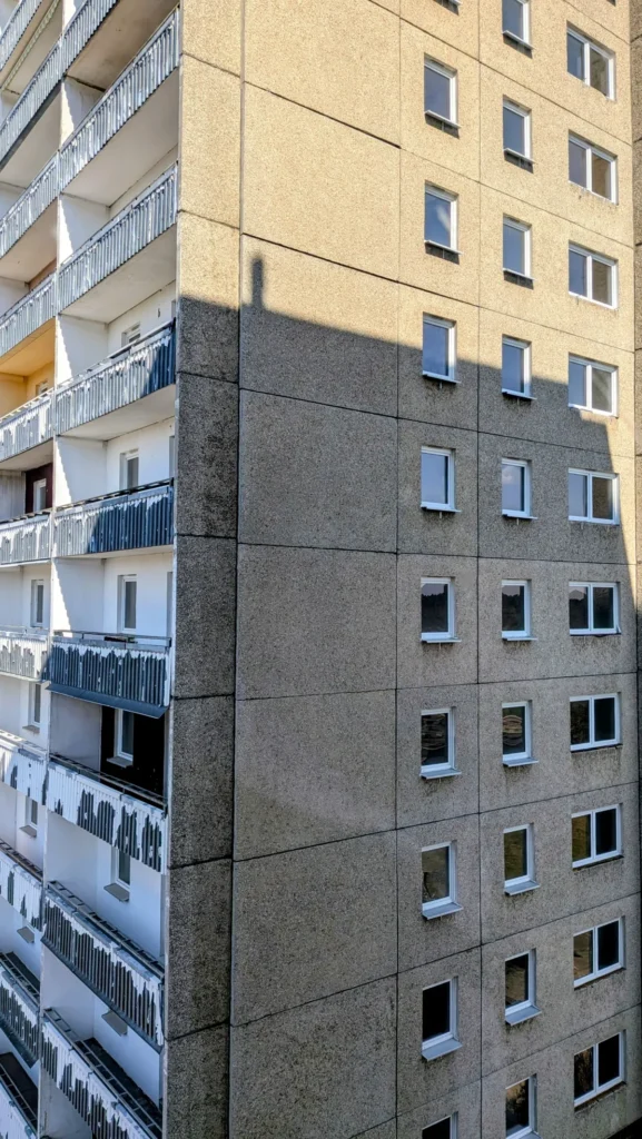 Fassade des Plattenbauhochhauses an der Mittelschleuse mit Waschbetonplatten und Balkonbrüstungen im Streiflicht