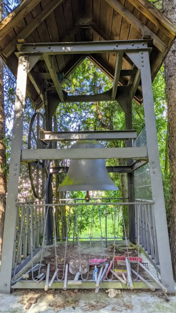 Hölzerner Glockenstuhl mit Glocke auf dem Friedhof an der Dorfstraße in Falkenberg