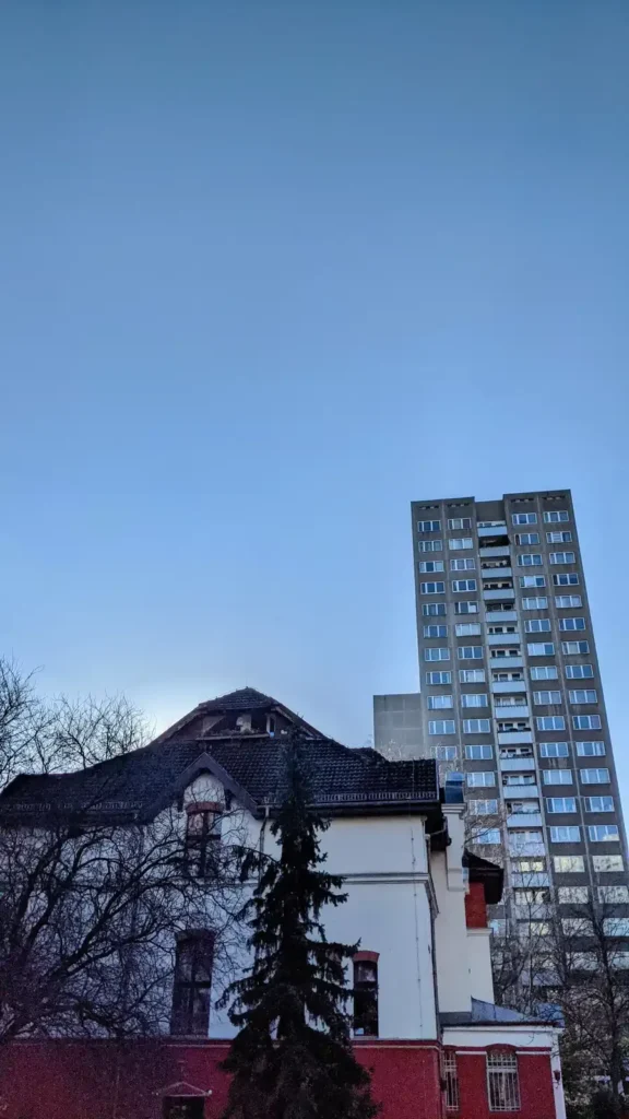 Villa am Fennpfuhl am Südrand des Fennpfuhlparks, dahinter ein Plattenbau-Hochhaus