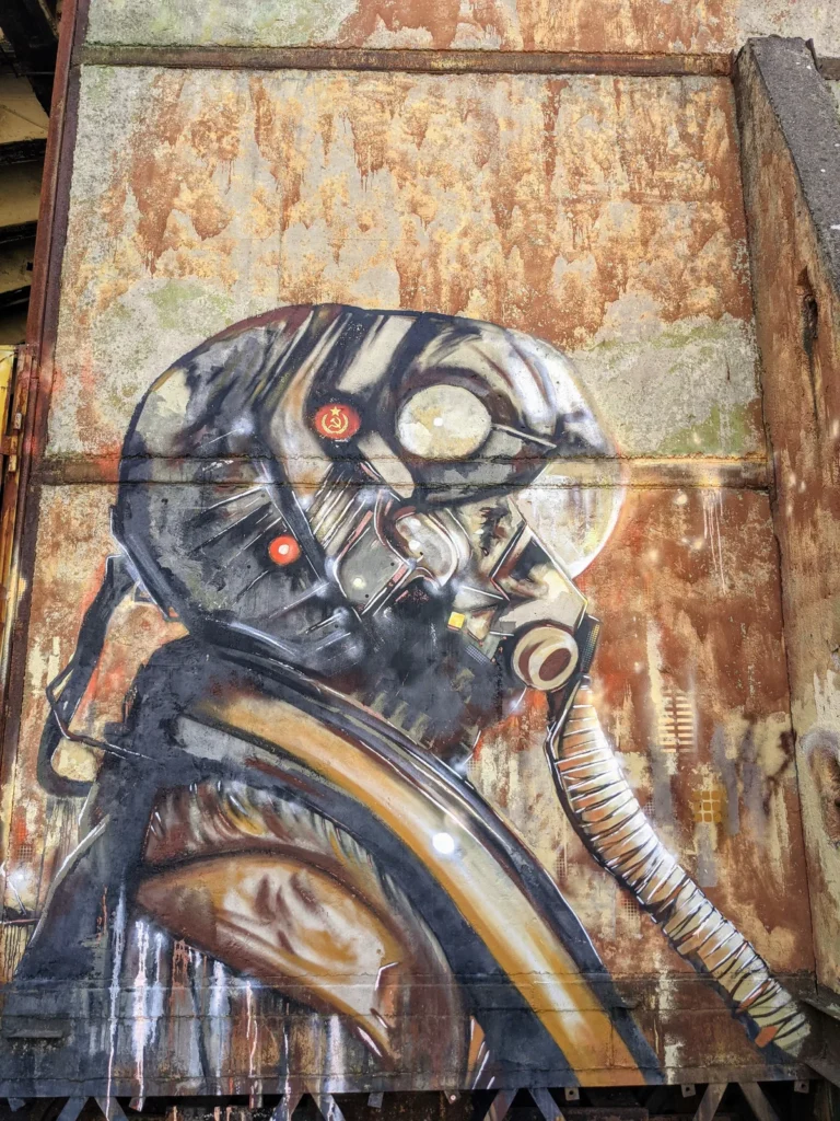 Graffito eines Kopfes mit Pilotenhelm und Atemschlauch auf dem Gelände bei Brand