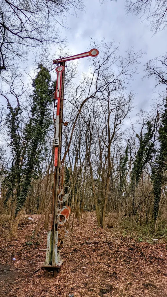 Altes rostrot-weißes Formsignal mit Schild E zwischen Bäumen bei Stahnsdorf