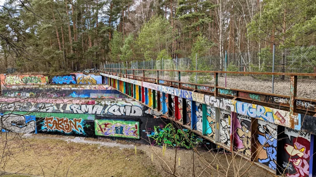 Lange Brücke mit Graffiti-Bildern, darunter weitere Tags an der Böschung, bei Dreilinden