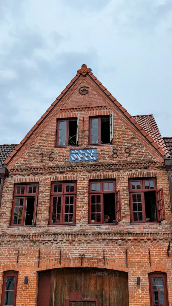 Backsteinhaus mit Giebel und blauem Schild in Friedrichstadt