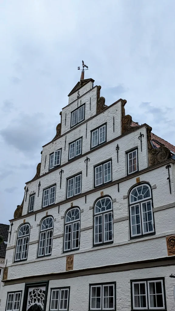 Weißes Giebelhaus mit Treppengiebel und Wetterfahne in Friedrichstadt