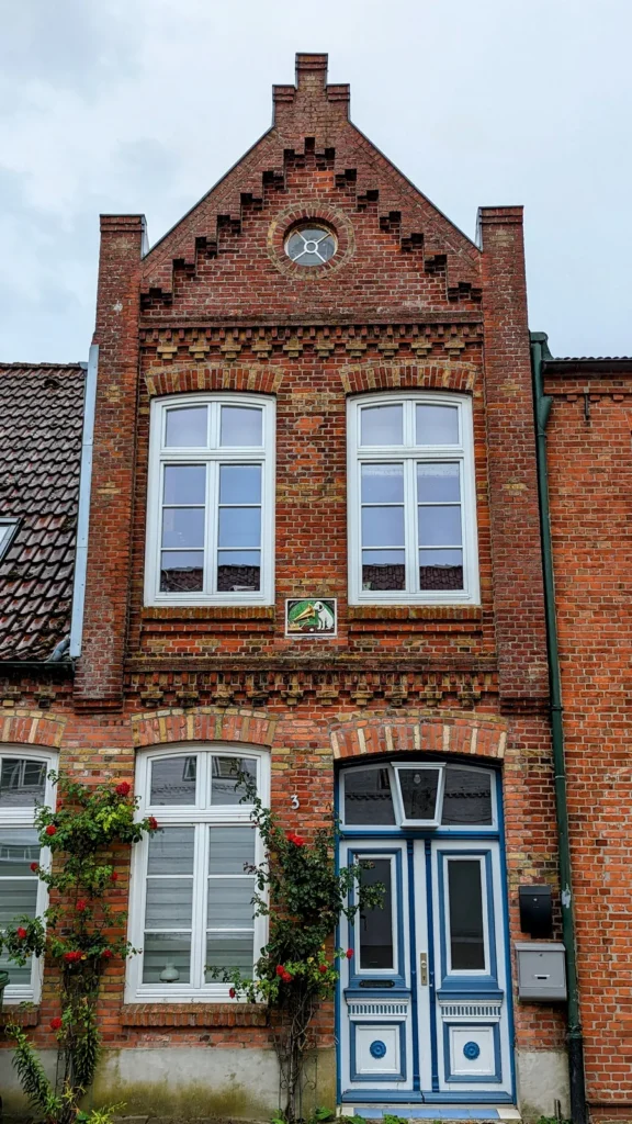 Backsteinhaus mit verziertem Treppengiebel und blauer Tür in Friedrichstadt