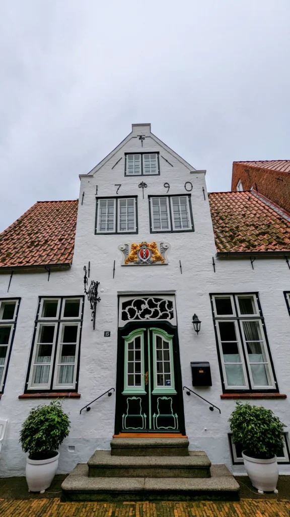 Weißes Giebelhaus mit Wappen und grüner Tür in Friedrichstadt