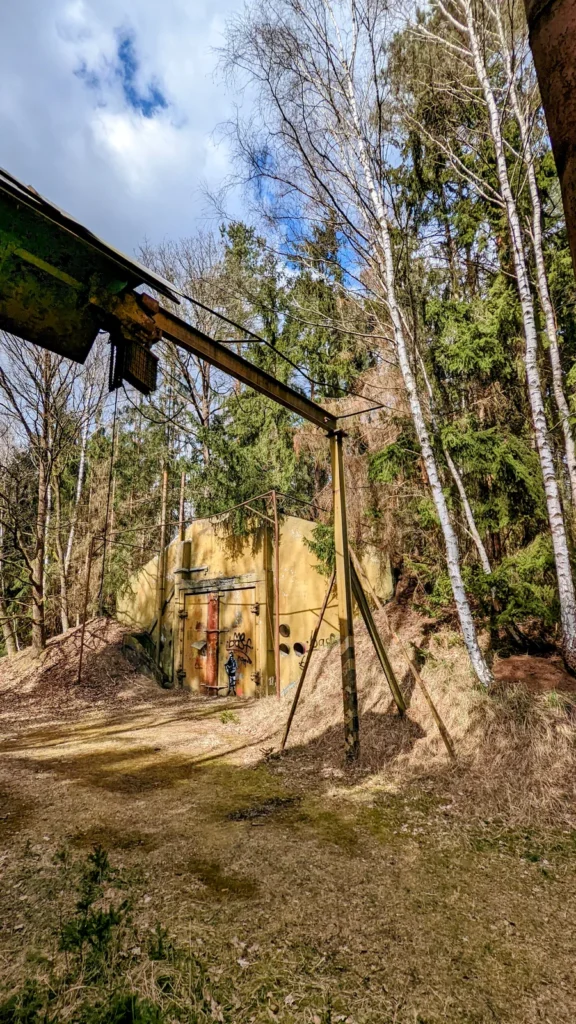 Portalkran vor einem erdüberdeckten Betonbau im Wald
