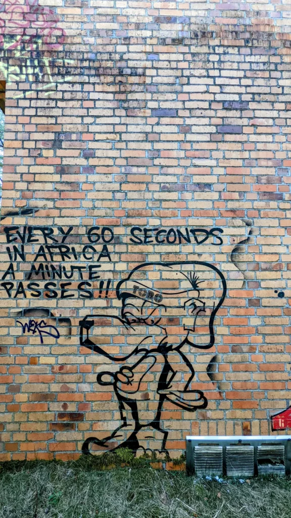 Backsteinwand mit schwarzer Tierfigur und dem Schriftzug „Every 60 seconds in Africa a minute passes“