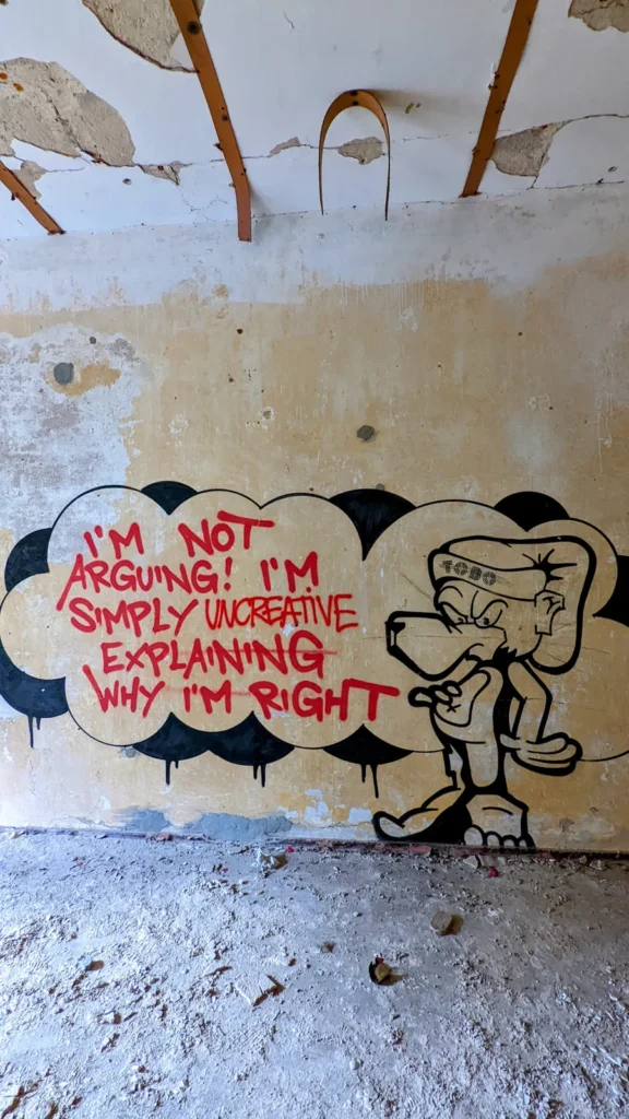 Gelbe Wand mit Sprechblase „I’m not arguing! I’m simply explaining why I’m right“ und Tierfigur