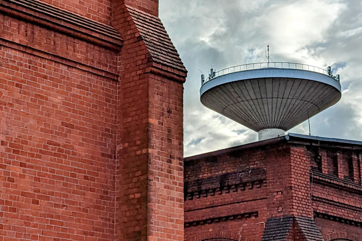 Neuer Wasserturm mit pilzförmigem Behälter hinter Backsteinbauten im ehemaligen Gaswerk Mariendorf